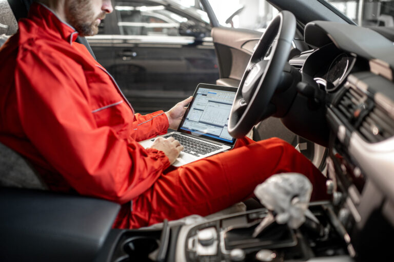 hombre técnico con portátil reprogramando un coche